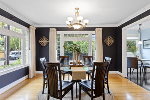 Deep navy walls, white crown molding, corner windows on two sides. The dining room doesn't whisper.