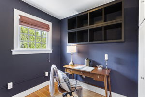 Navy walls, full-wall built-ins, a window into the trees. Home office, music room, or walk-in closet — the room doesn't care which.