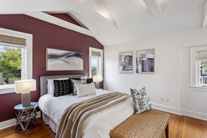 Vaulted ceilings with exposed beams, deep burgundy accent wall, original red fir floors, multiple windows. Upstairs, the Craftsman stops being modest.