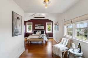 Nearly 400 square feet of vaulted, beamed, burgundy-anchored primary bedroom. The sitting area by the window is not an afterthought.