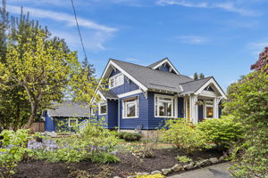 Navy and white, yellow door, corner lot at the top of the hill. A hundred years in — and the Lacewing landscape is hitting its May stride.