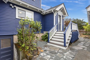 Off the kitchen, the split staircase drops you east to the garden or west toward the driveway and garage. New flagstone, exterior basement access just left of the stairs.