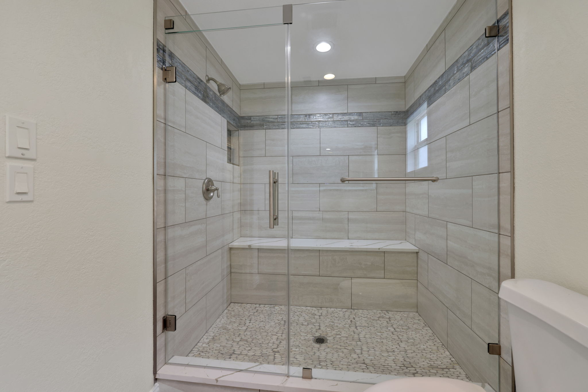 This bathroom features a spacious, modern walk-in shower with elegant tile work, a glass enclosure, and a built-in bench for added convenience.