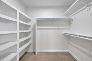 Spacious walk-in closet with multiple white shelves and clothing rods, perfect for organized storage.