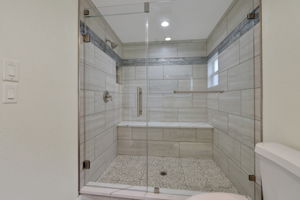 This bathroom features a spacious, modern walk-in shower with elegant tile work, a glass enclosure, and a built-in bench for added convenience.