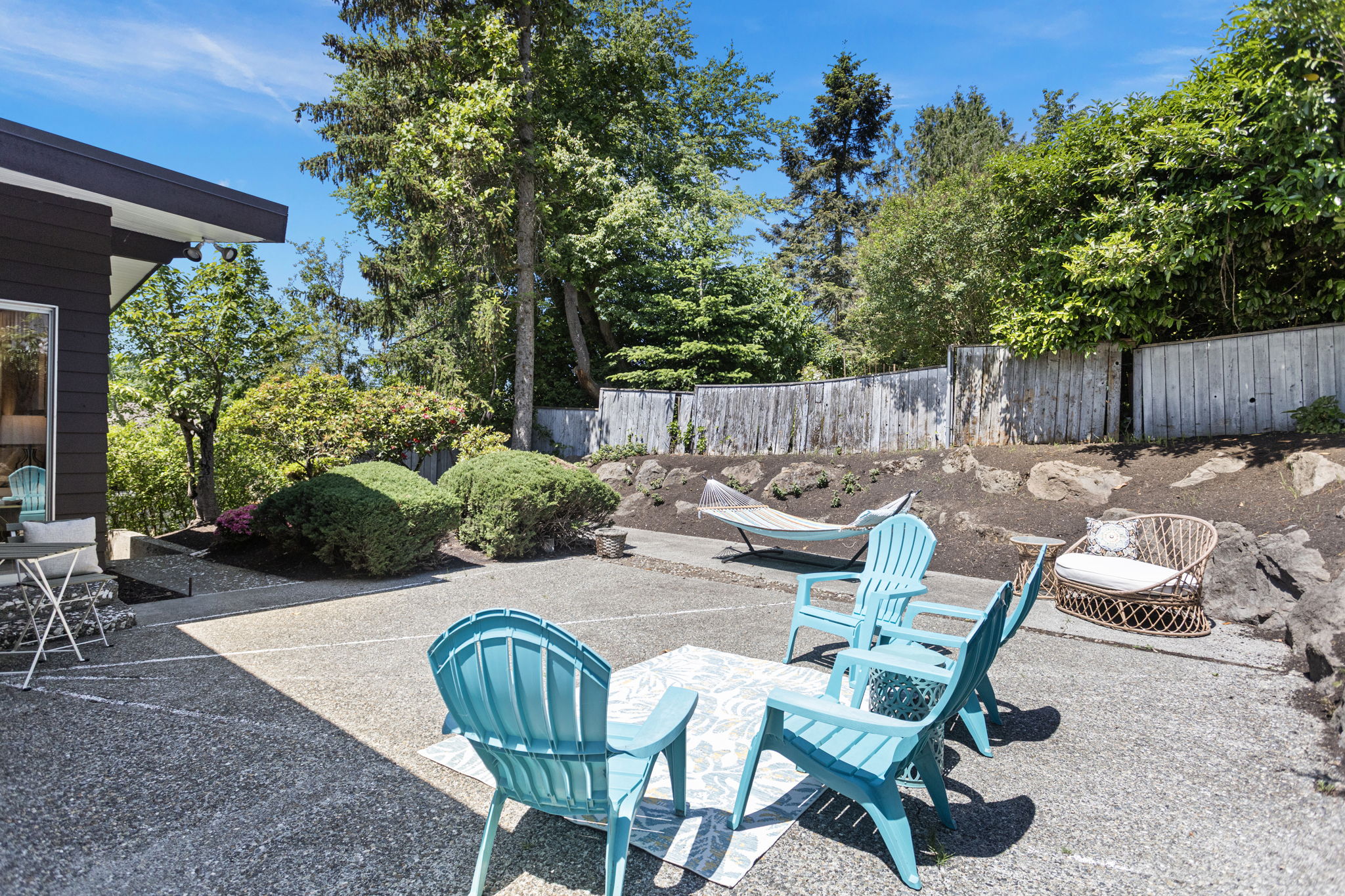 Concrete aggregate patio, mature shrubs, boulders, hammock, full sun. Seward Park summer starts here.