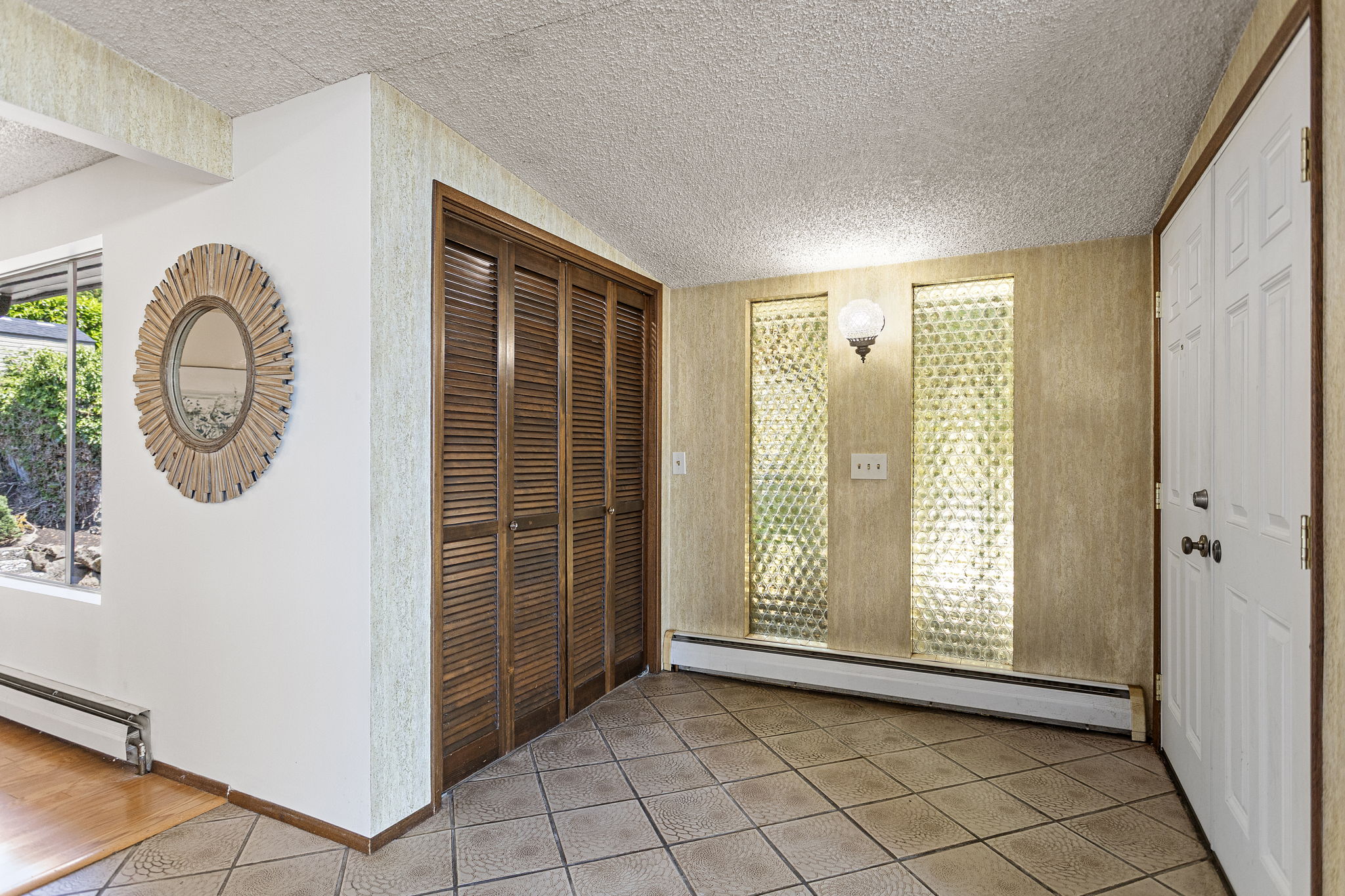 Twenty-seven feet of foyer. The house announces itself before you reach the living room. Original 1965 — pebbled glass sidelights, louvered closet doors, embossed tile floor.