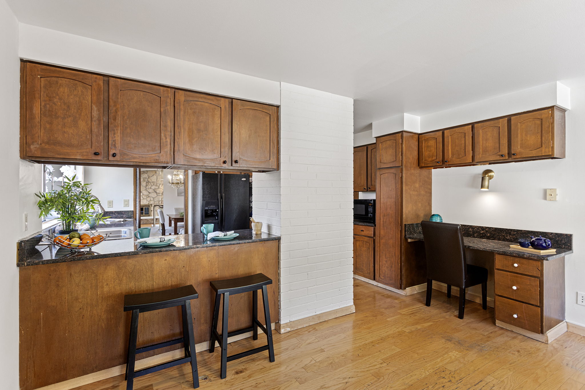 Pass-through counter with bar seating, built-in desk, painted brick column. Casual dining, homework, morning coffee — same room.