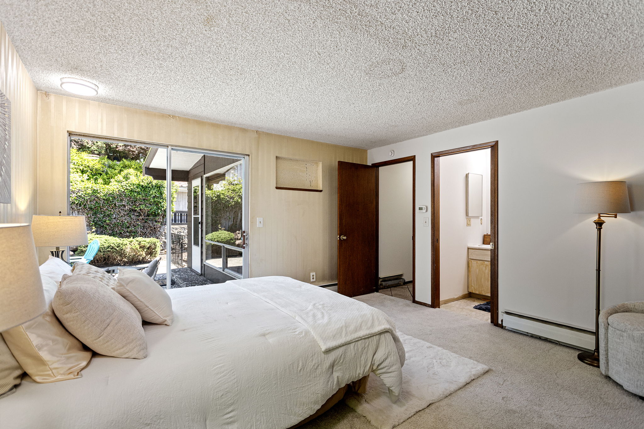 The other angle — patio access, en suite bath just through the door, radiant heat. Every base covered but the updates. A blank slate — yours to make, with brand-new carpet already in place.