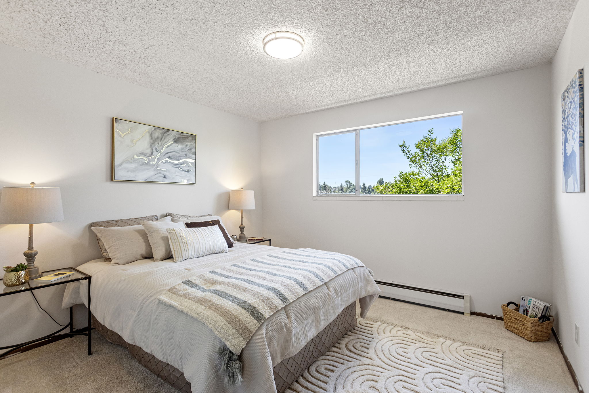 The second bedroom has room for a queen, a west-facing window full of trees, and brand-new carpet underfoot.