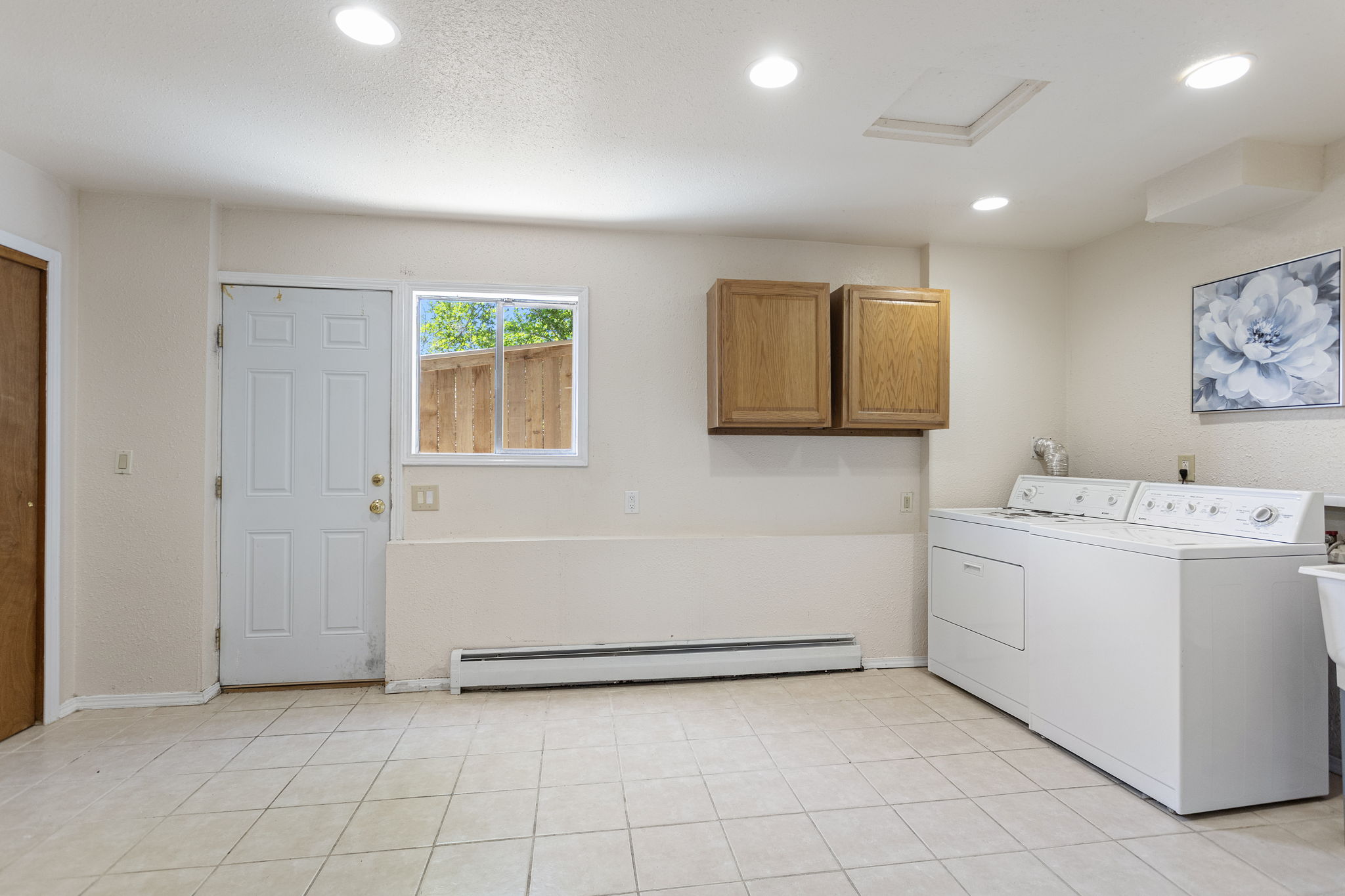 Large laundry room with exterior door, two closets with lights, upper cabinets, washer/dryer, recessed lighting. The start of a future second kitchen conversation for this level — buyer to verify all uses and permitting.