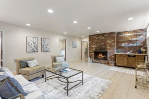 The lower level rec room — nearly 500 square feet, 8-foot ceilings, brick fireplace wall, wet bar, recessed lighting, tile floor. The lower level's main event.