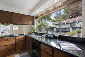 The window makes the kitchen. Granite counters, recessed lighting, yard view while you do the dishes. Pass-through to the breakfast nook and second dining area beyond.