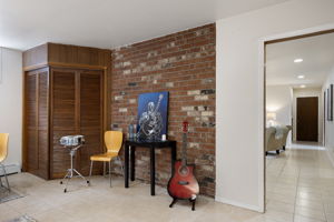 The same chimney that anchors the rec room fireplace rises through here as exposed brick. (The lower level has a spine.) Guitar optional.