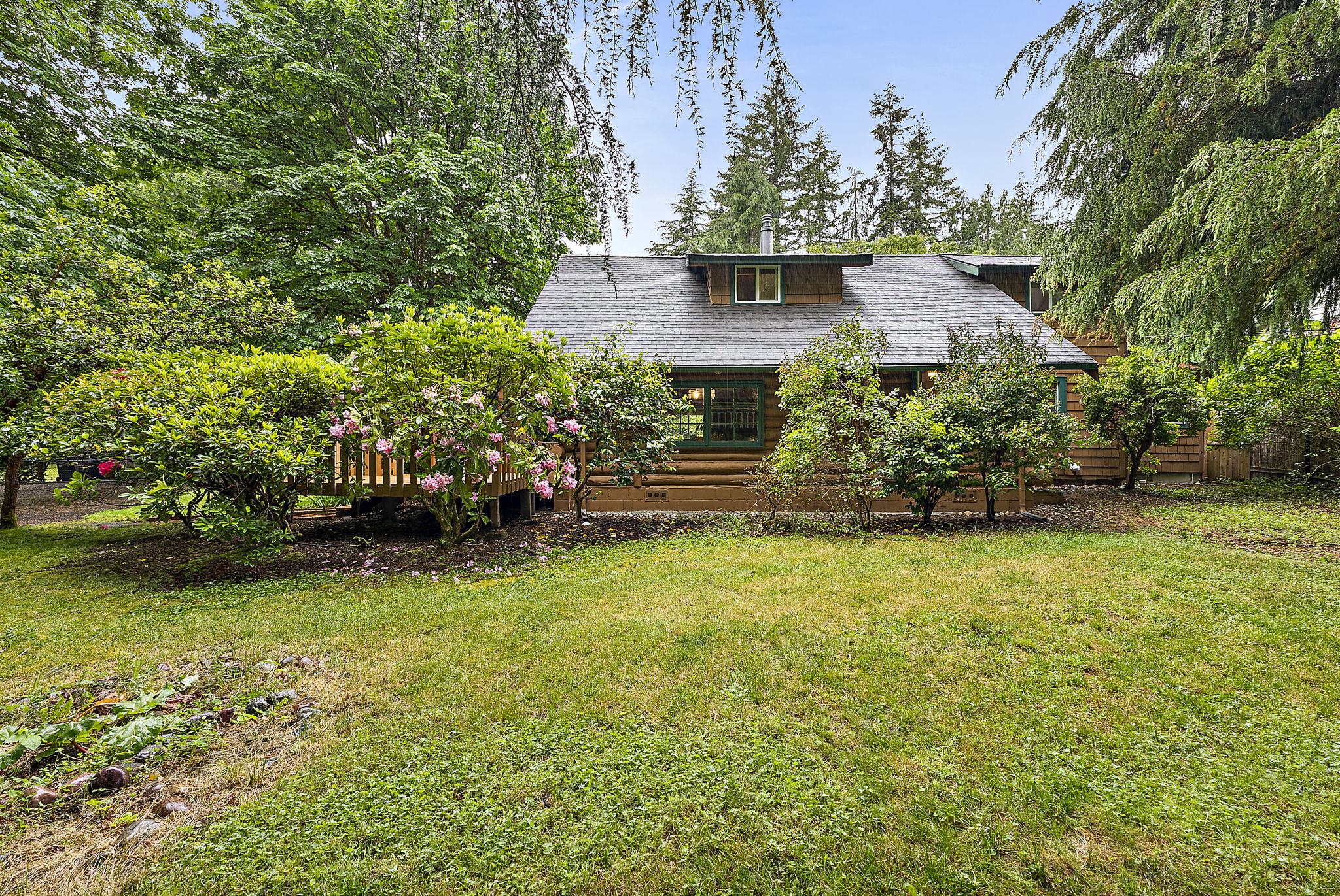 View of front of the home with front porch off to the left. Tons of beautiful foliage.