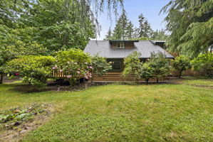 View of front of the home with front porch off to the left. Tons of beautiful foliage.