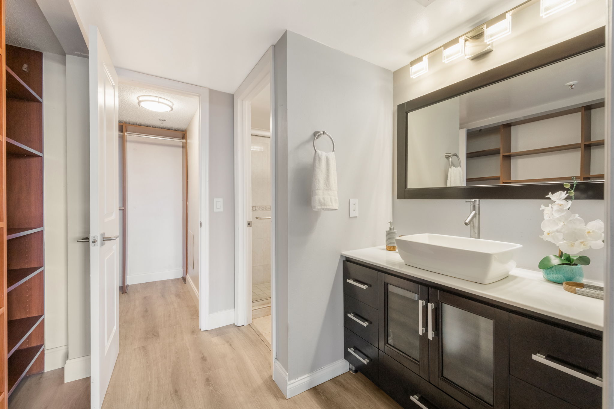 Updated Primary Ensuite. Note the additional built-in storage to the left. Shower and toilet to the right with privacy door and entrance to the walk-in closet in the background.