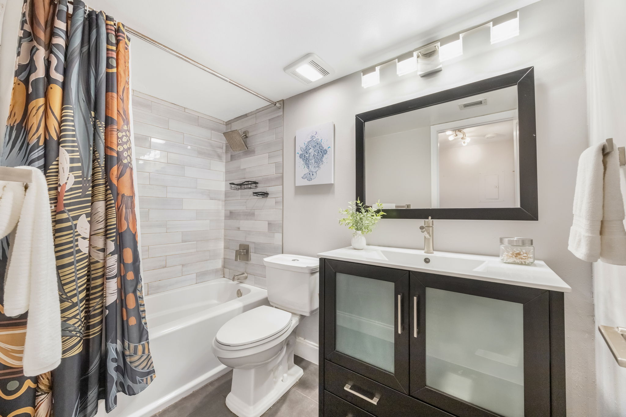 Secondary Hall Bath offers updated vanity and tub shower combo with rain shower head and beautiful subway tile.