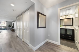 View from entry foyer. To the right is secondary full bath.  The first hall closet holds the laundry, while the second is mechanical. Notice the wide baseboards, plank luxury vinyl floors and can lights added during the remodel.