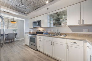 The updated kitchen features white shaker cabinetry, updated lighting, cool faux tin ceiling and stainless appliances.