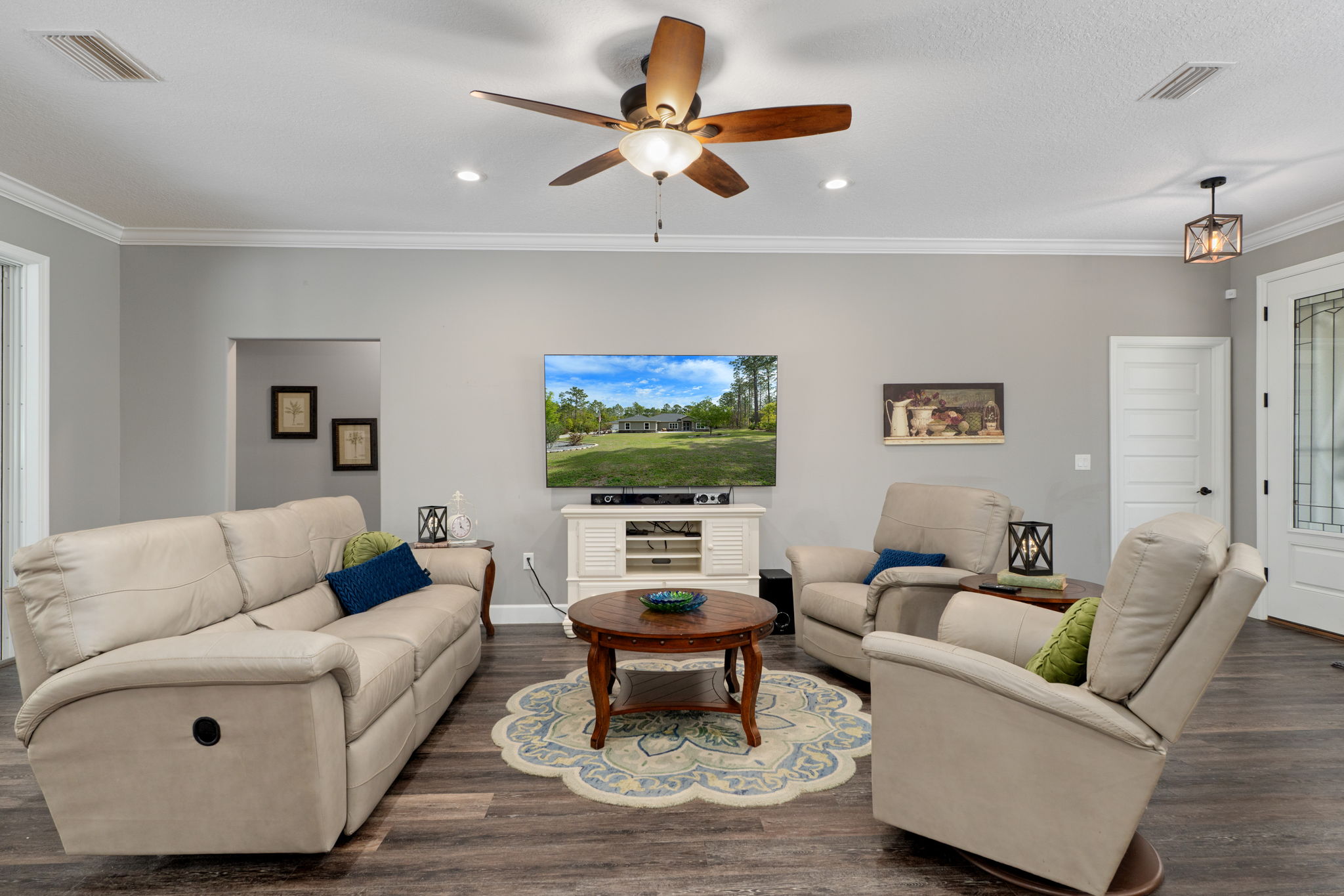 The great room, opposite the kitchen. The closed solid door on the right leads to the flex room, currently used as an office. The open doorway on the left leads to the two guest bedrooms and hall bath.
