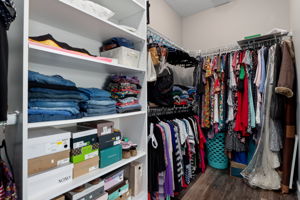 The primary suite's walk-in closet features built-in shelving.