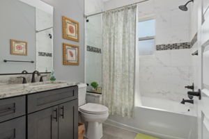 The guest hall bath features comfort height vanity and toilet, along with an accent ribbon of tile in the tub surround and built in seat at the end of the tub.