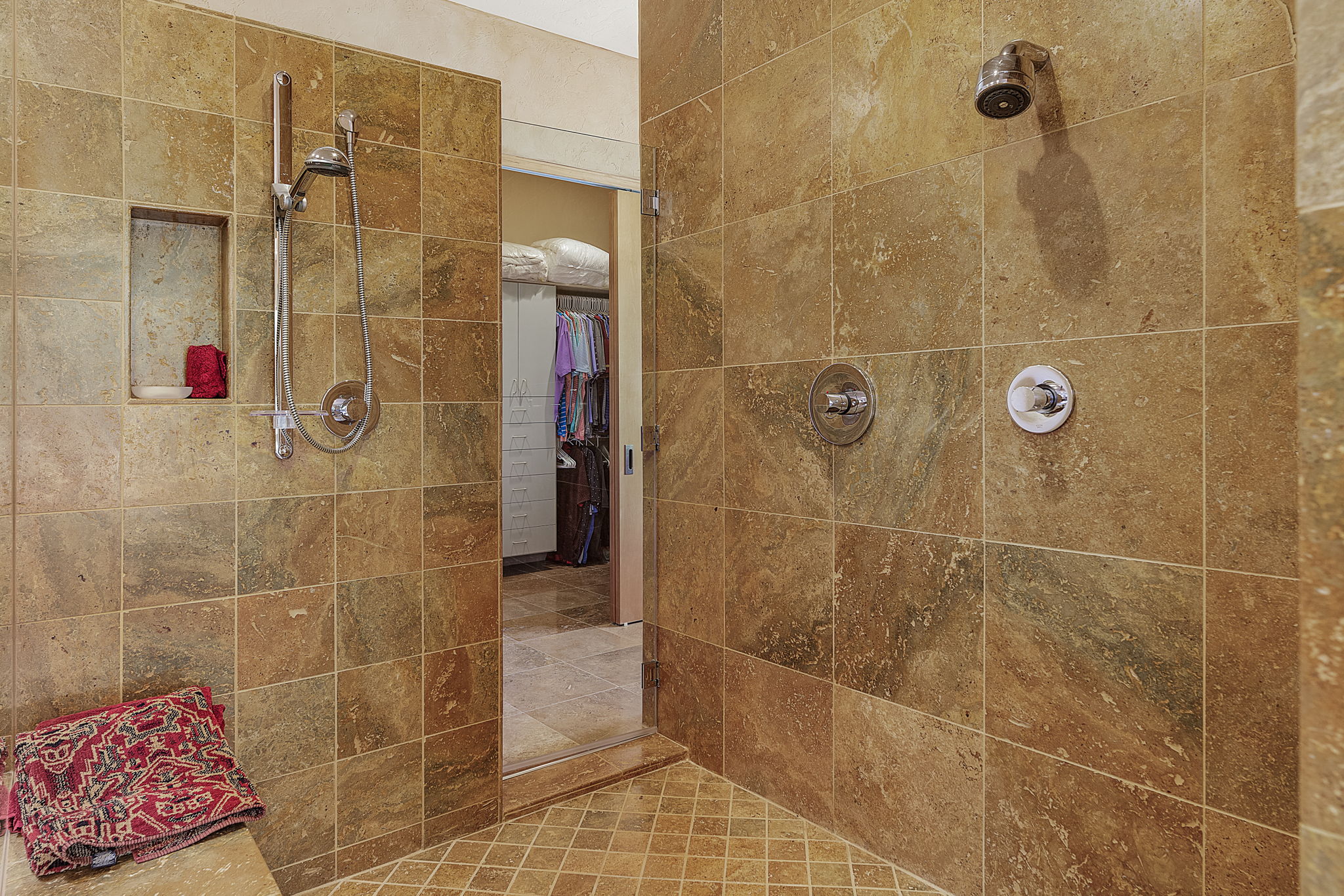 The central walk-in shower has a bench seat and two shower heads for a comfortable and luxurious experience.