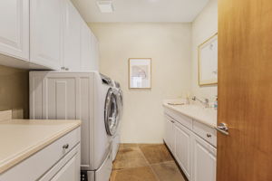 Laundry Room includes a front-loading washer and dryer, a utility sink, and built-in cabinets with ample countertop space.