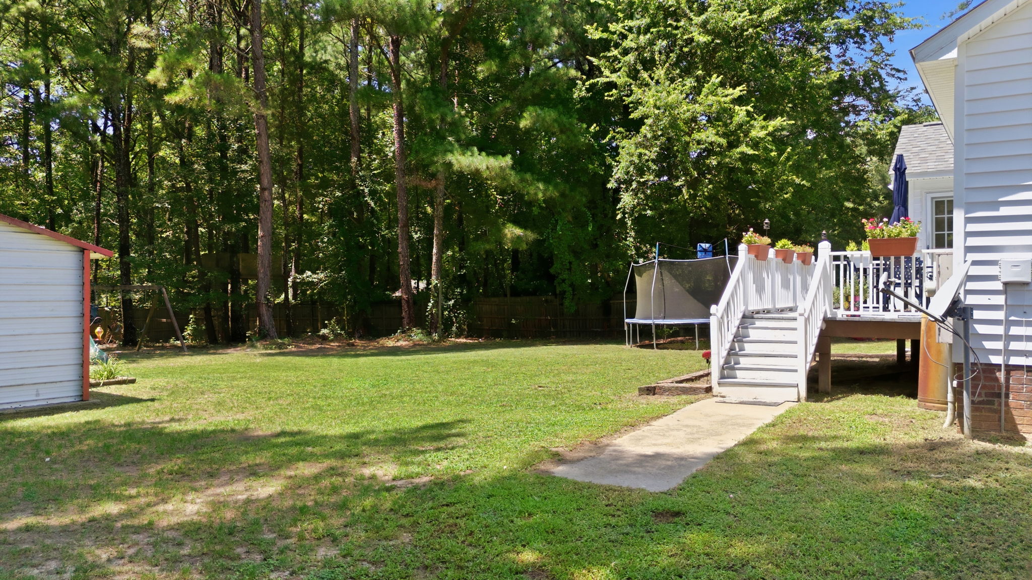 Flat backyard bordered by mature trees