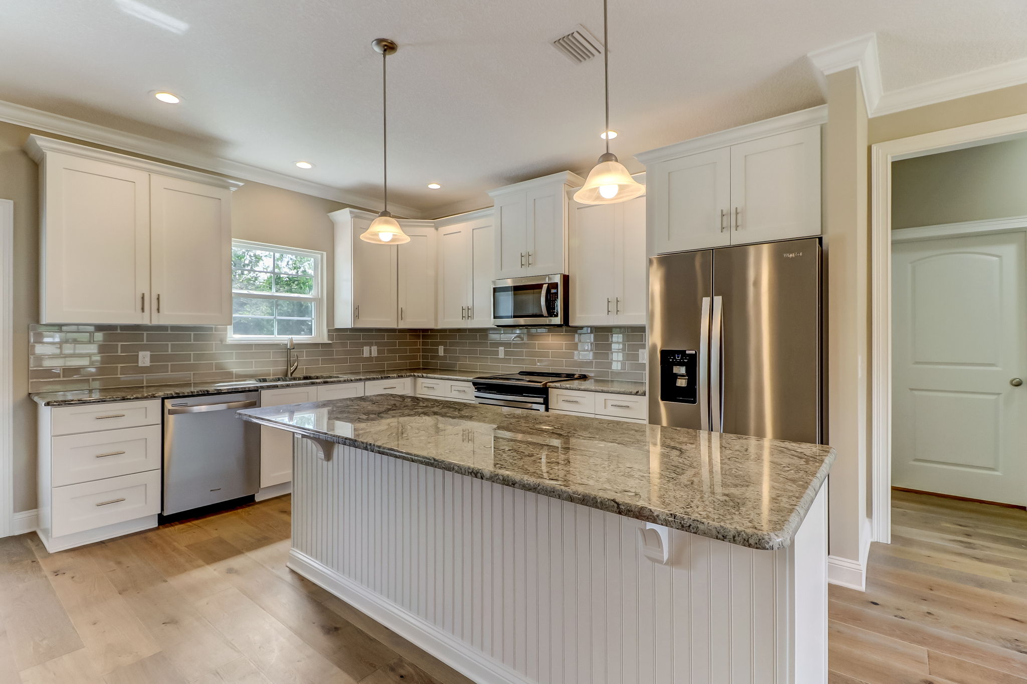 The kitchen is bright and elegant with granite countertops and island, 42' soft close cabinets, and Whirlpool appliances.