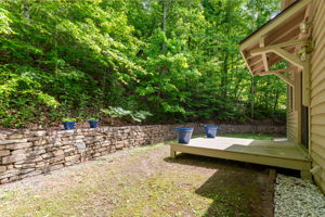 Back yard with stone retraining wall and covered porch