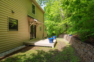 Back yard with stone retraining wall and covered porch