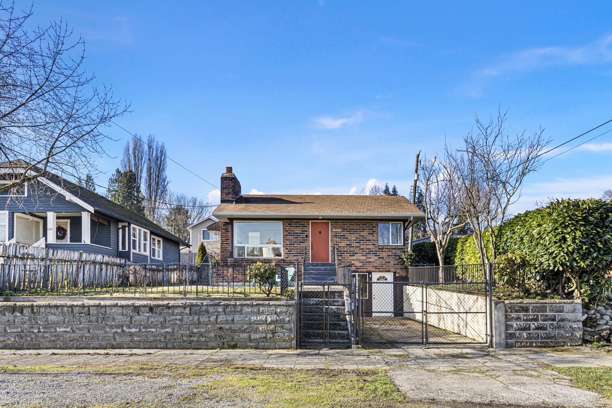 Gated front drive and mature plantings frame the home, balancing openness with a sense of separation from the street.