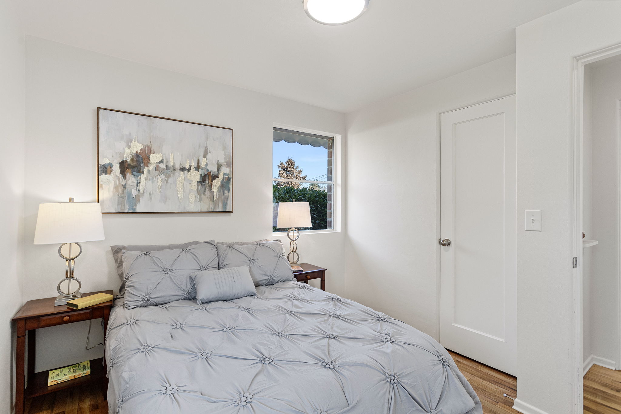 A quiet back bedroom with a north-facing window, hardwood floors, and a simple, functional footprint.