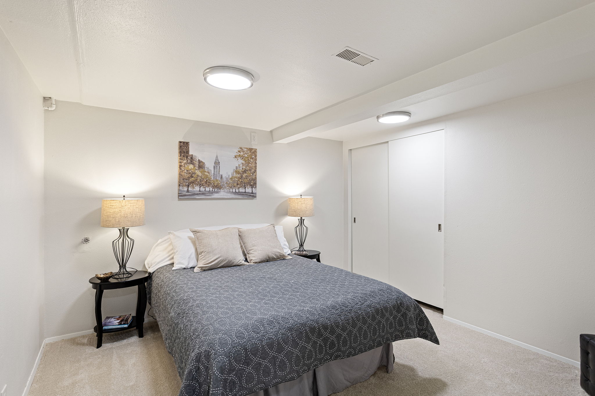 A generously sized lower-level bedroom with new carpet and updated lighting; non-conforming due to the absence of a window.