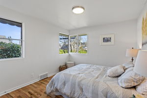 The front bedroom is the most generously sized in the home, with corner windows facing east and north plus an additional north-facing window for consistent natural light.