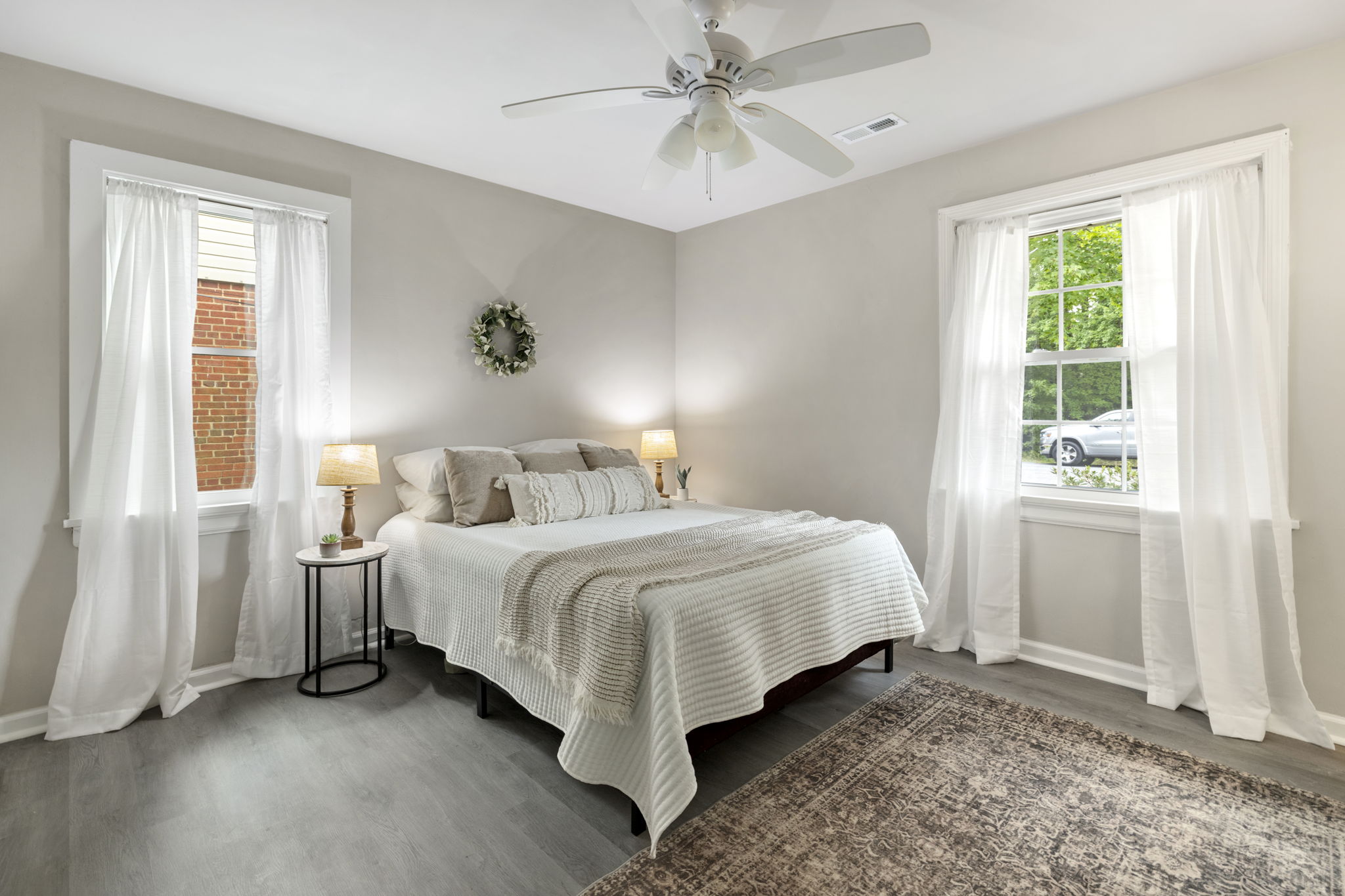 Front 1st floor primary bedroom with new Anderson windows, LVP flooring, & ceiling fan.