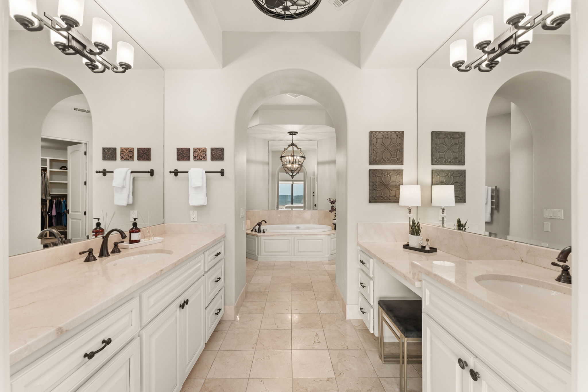 Step into the primary bathroom featuring a private dressing area, sleek double vanity, and timeless marble details.