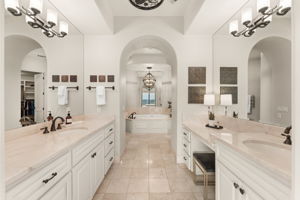 Step into the primary bathroom featuring a private dressing area, sleek double vanity, and timeless marble details.