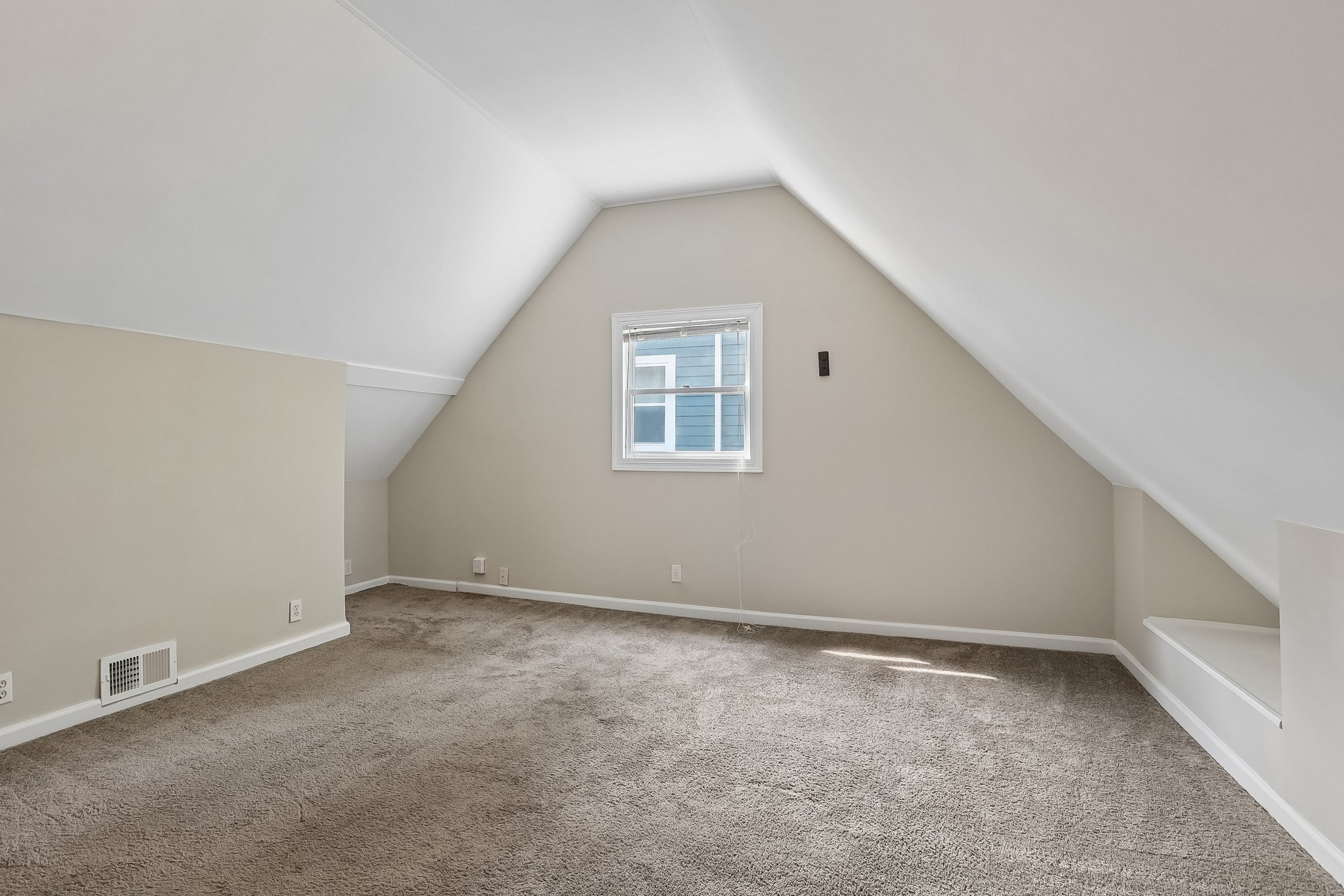 Upstairs spacious bonus room with charming sloped ceilings creates a cozy retreat with unmistakable Cape Cod character