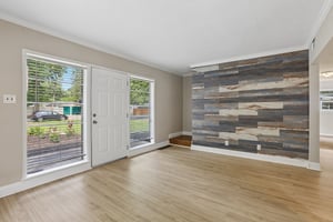 Gather and unwind in a sun-filled living room where warm flooring and a dramatic wood accent wall add instant character.