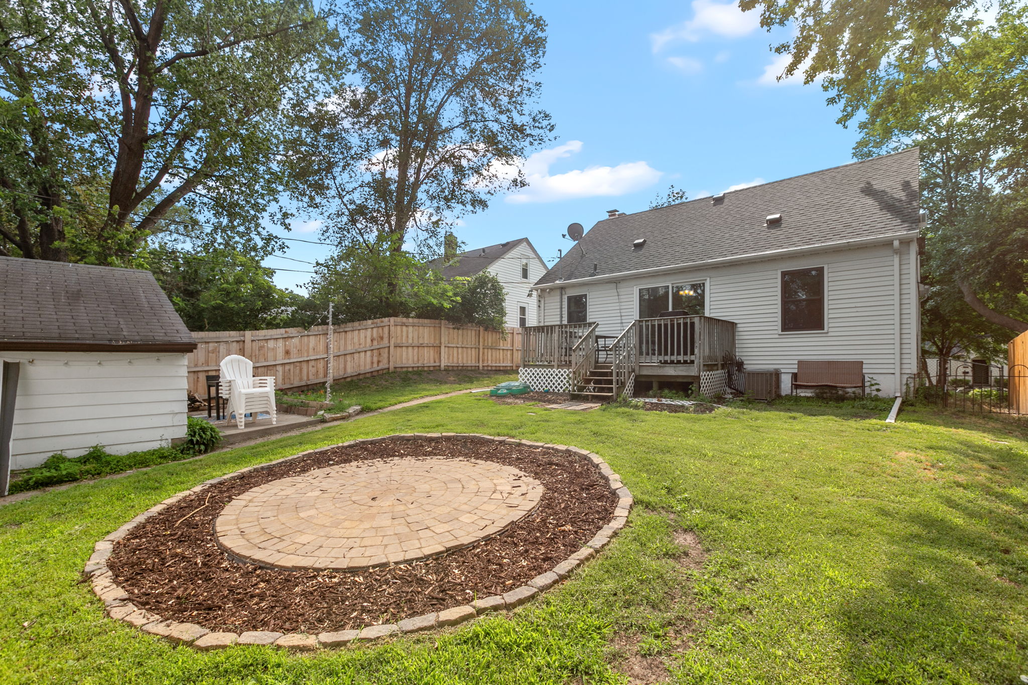 A large wooden rear deck, circular paver patio, and full-coverage wooden steel-post privacy fence mean you're equipped for entertaining, gardening, and pets at 5549 27th Avenue S.