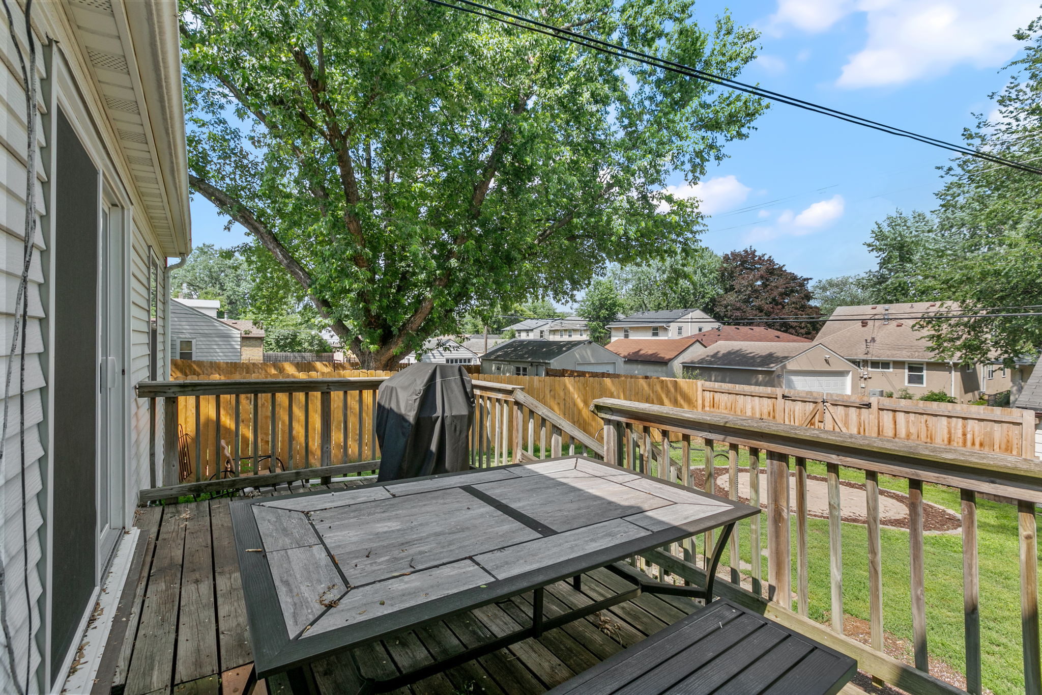 A large wooden rear deck, circular paver patio, and full-coverage wooden steel-post privacy fence mean you're equipped for entertaining, gardening, and pets at 5549 27th Avenue S.