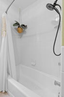 The bathroom at 5549 27th Avenue S is accessible from the main level of the home, with a conveniently wide vanity countertop and a full-height shower + bathtub.