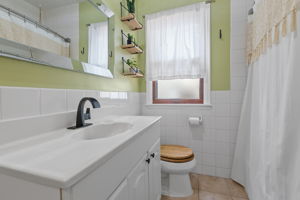 The bathroom at 5549 27th Avenue S is accessible from the main level of the home, with a conveniently wide vanity countertop and a full-height shower + bathtub.