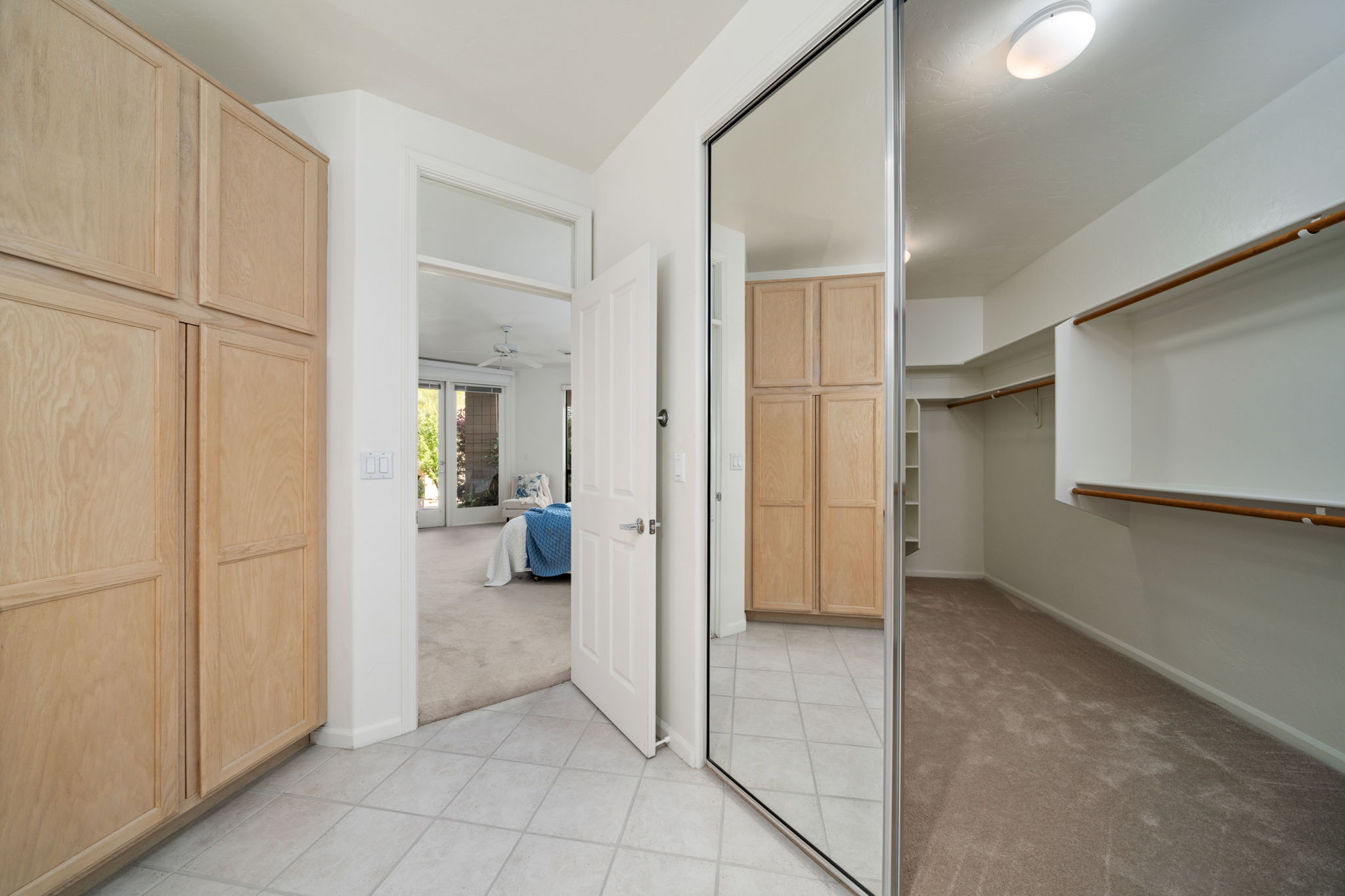 Storage cabinets and view to walk-in closet in the primary bathroom