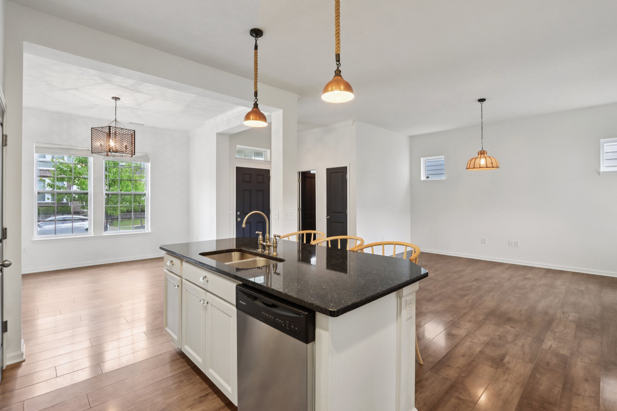 Center-stage island, pendant lighting, and open sightlines to the living room create a space that's both stylish and functional.