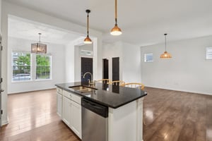 Center-stage island, pendant lighting, and open sightlines to the living room create a space that's both stylish and functional.