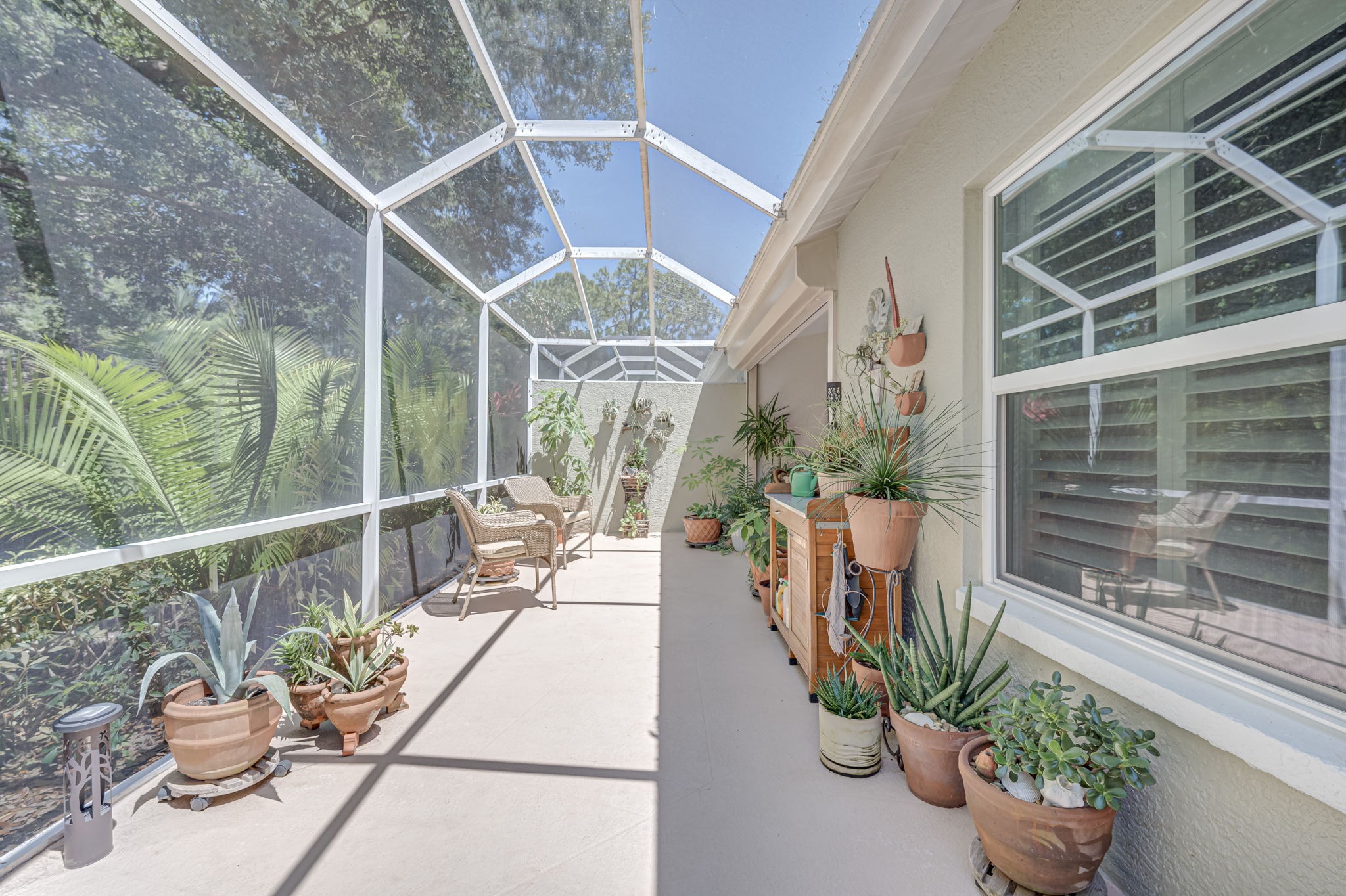Extended screened lanai enclosure providing a private outdoor oasis with panoramic views of the property's mature tropical landscaping